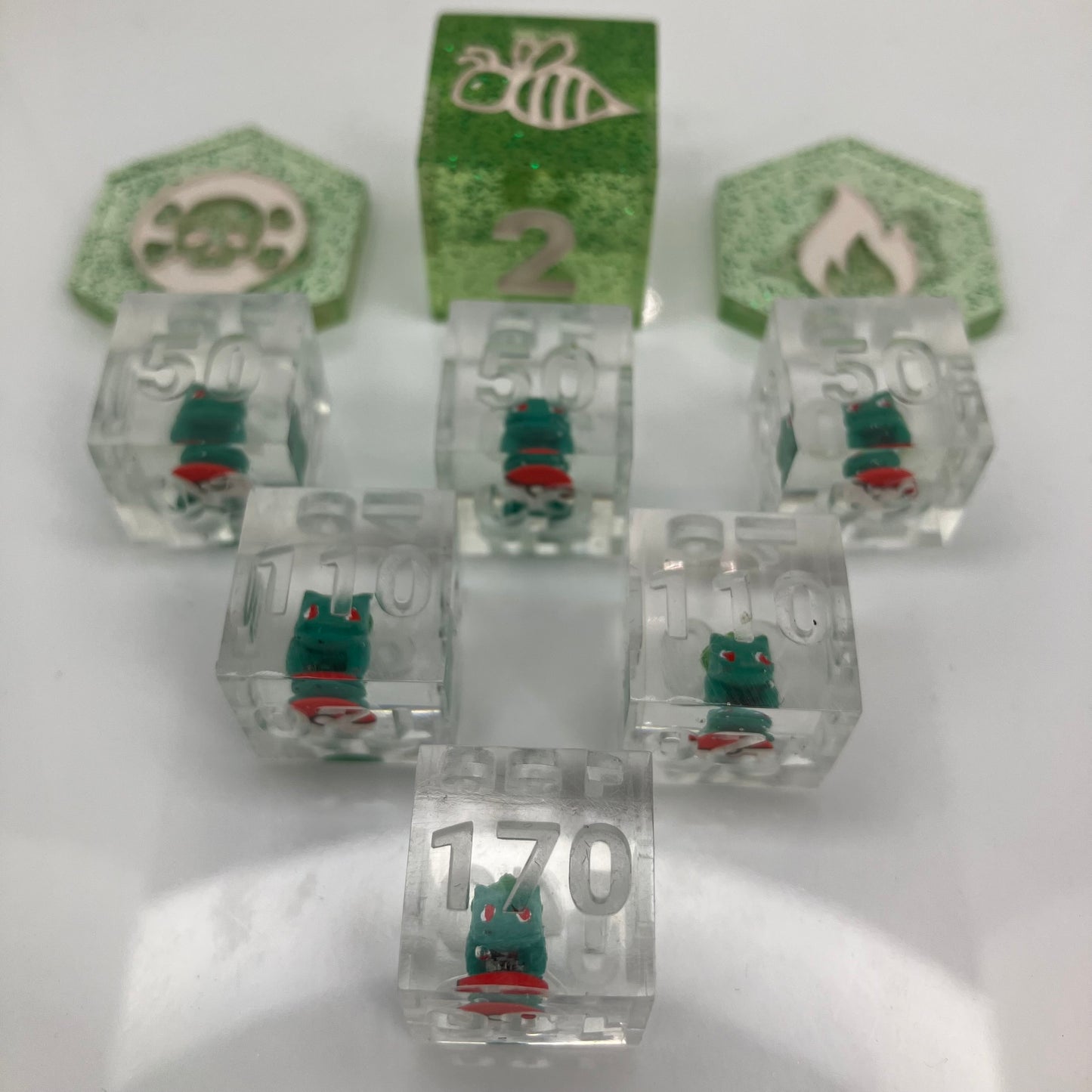 tiny hand painted bulbasaurs set in clear dice for the pokemon trading card game