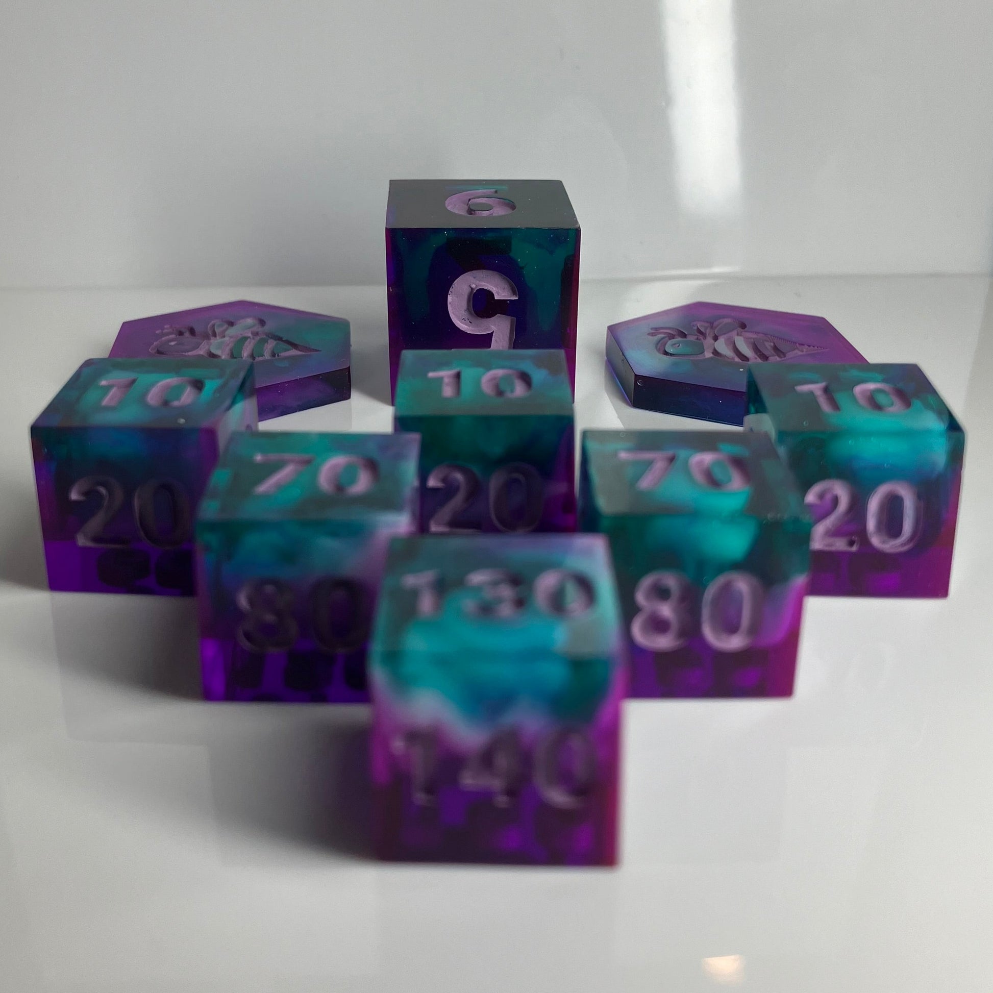 Set of purple and teal polyhedral dice with white clouds for Pokemon TCG