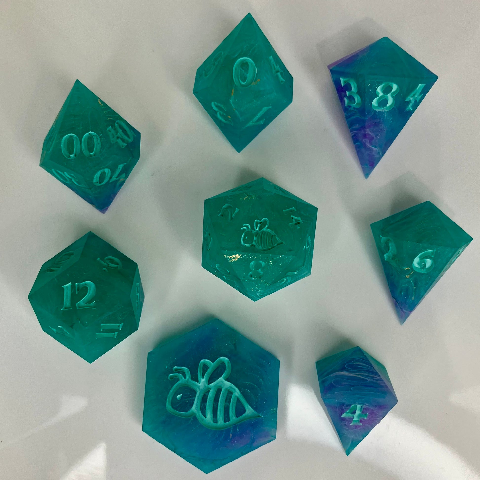 Set of teal polyhedral dice with numbers and symbols on a white background