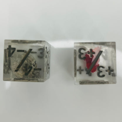 Two clear dice with black numbers with an embedded skull and heart