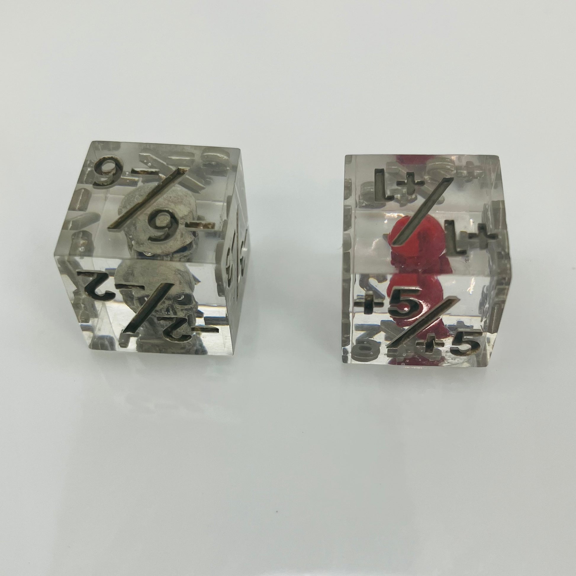 Two clear dice with black numbers with an embedded skull and heart