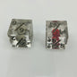 Two clear dice with black numbers with an embedded skull and heart