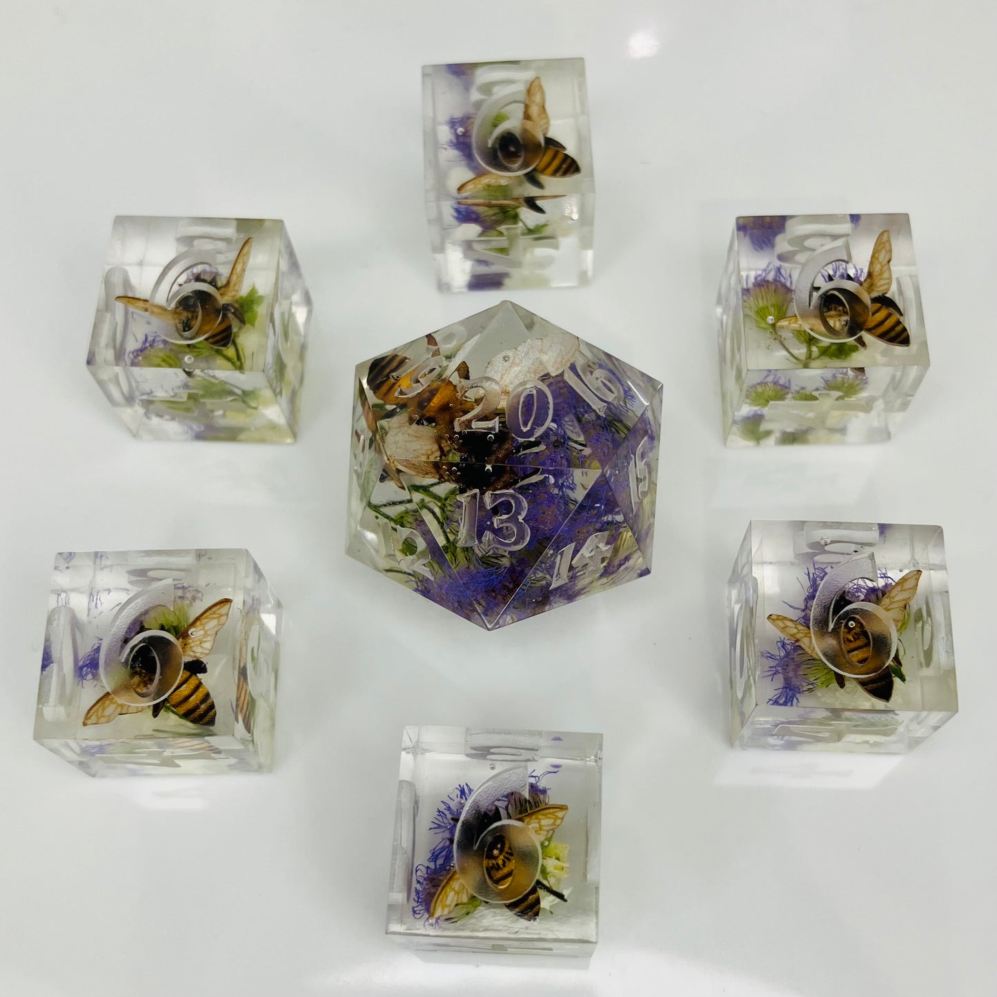 Set of crystal dice with embedded bees and flowers on a white background