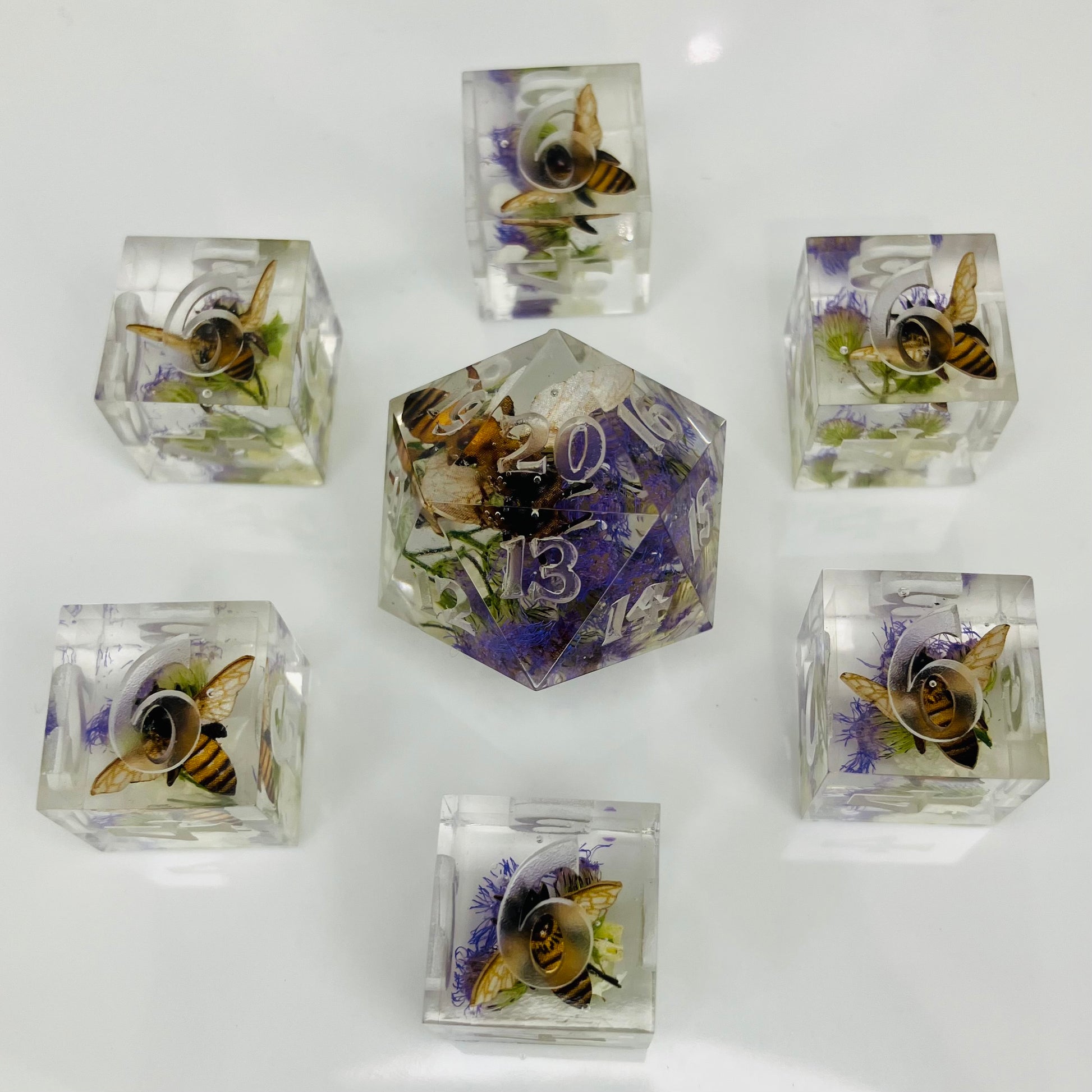 Set of crystal dice with embedded bees and flowers on a white background