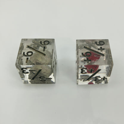 Two clear dice with black numbers with an embedded skull and heart