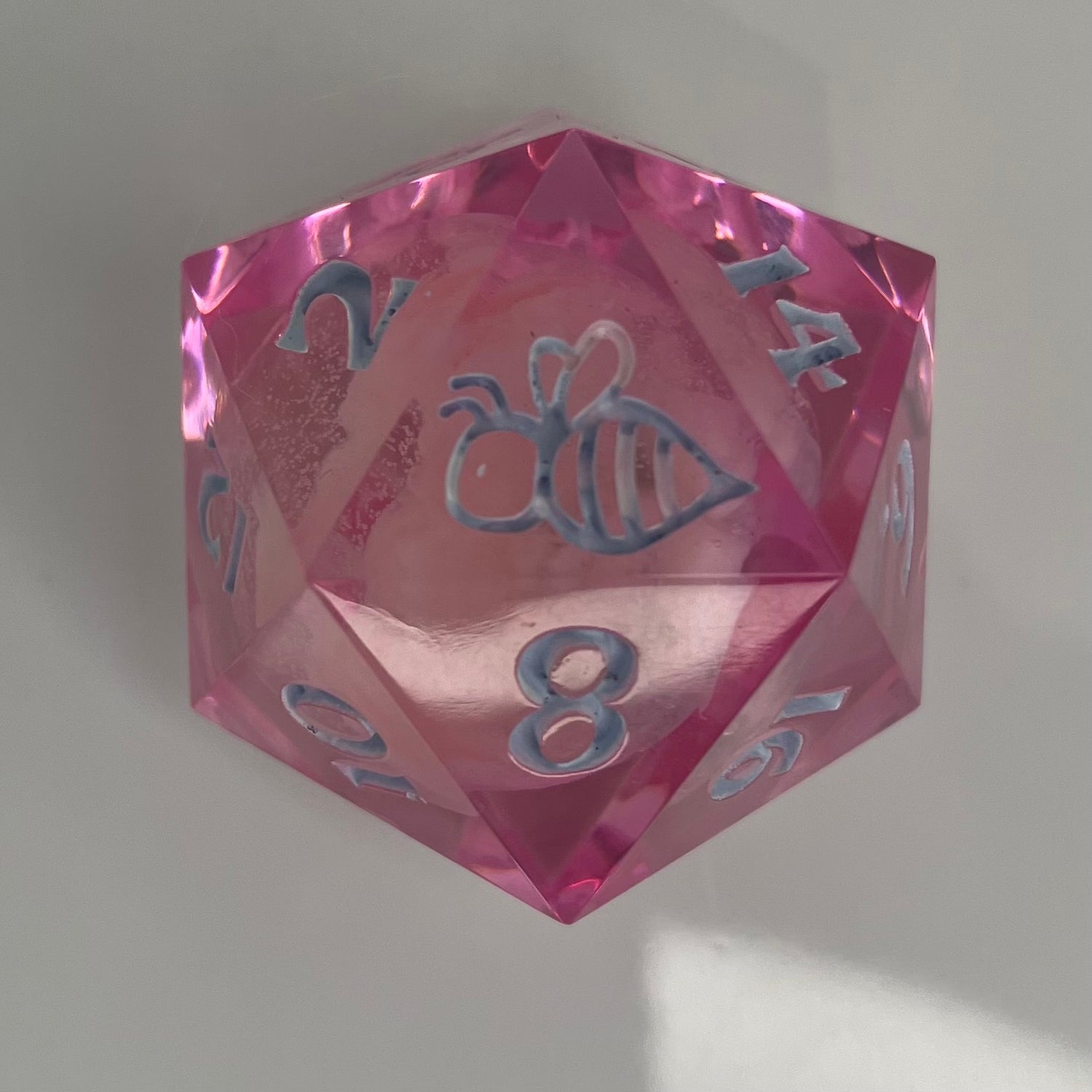 clear pink d20 with bee logo and 'moon' insert
