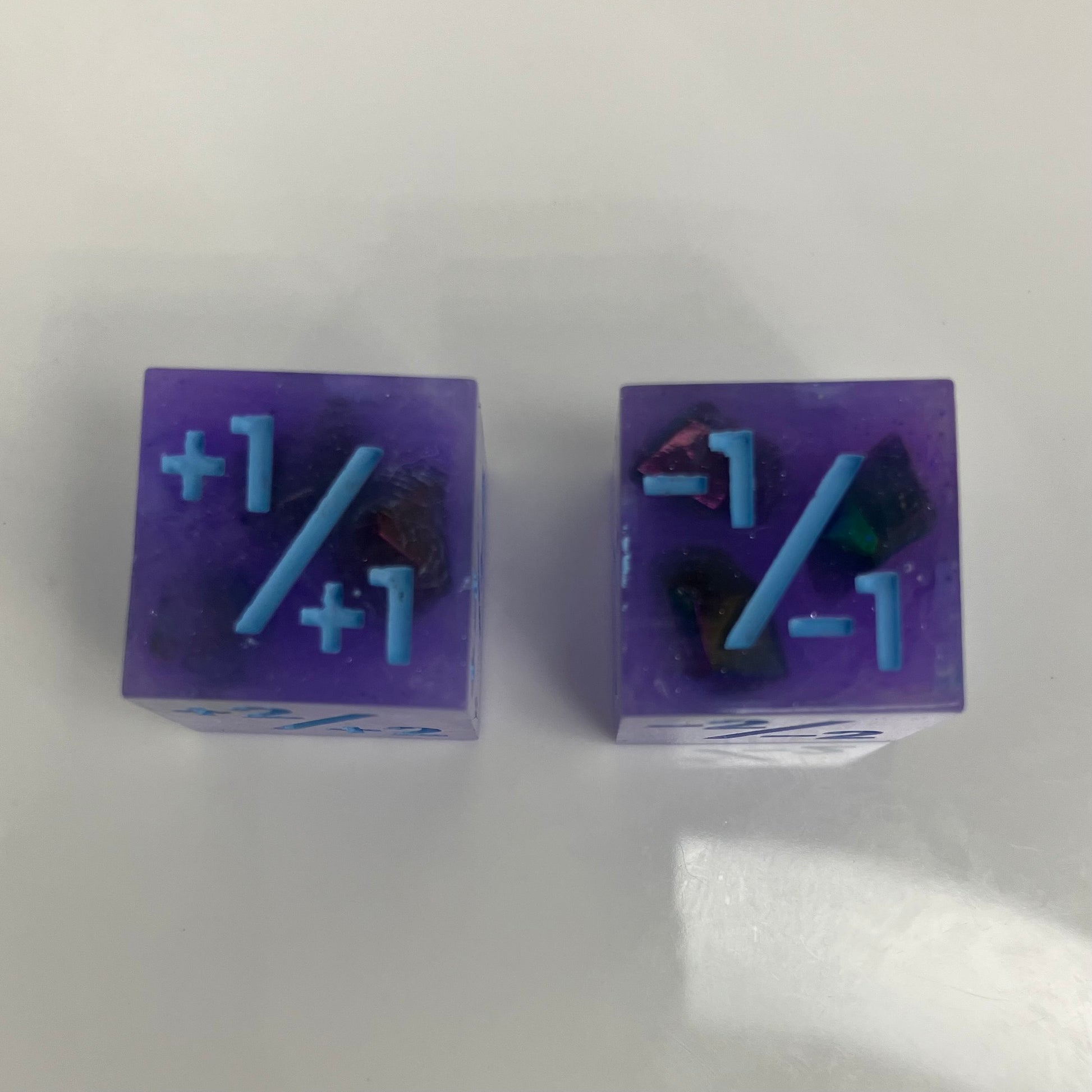 Two purple dice with blue numbers and iridescent rocks