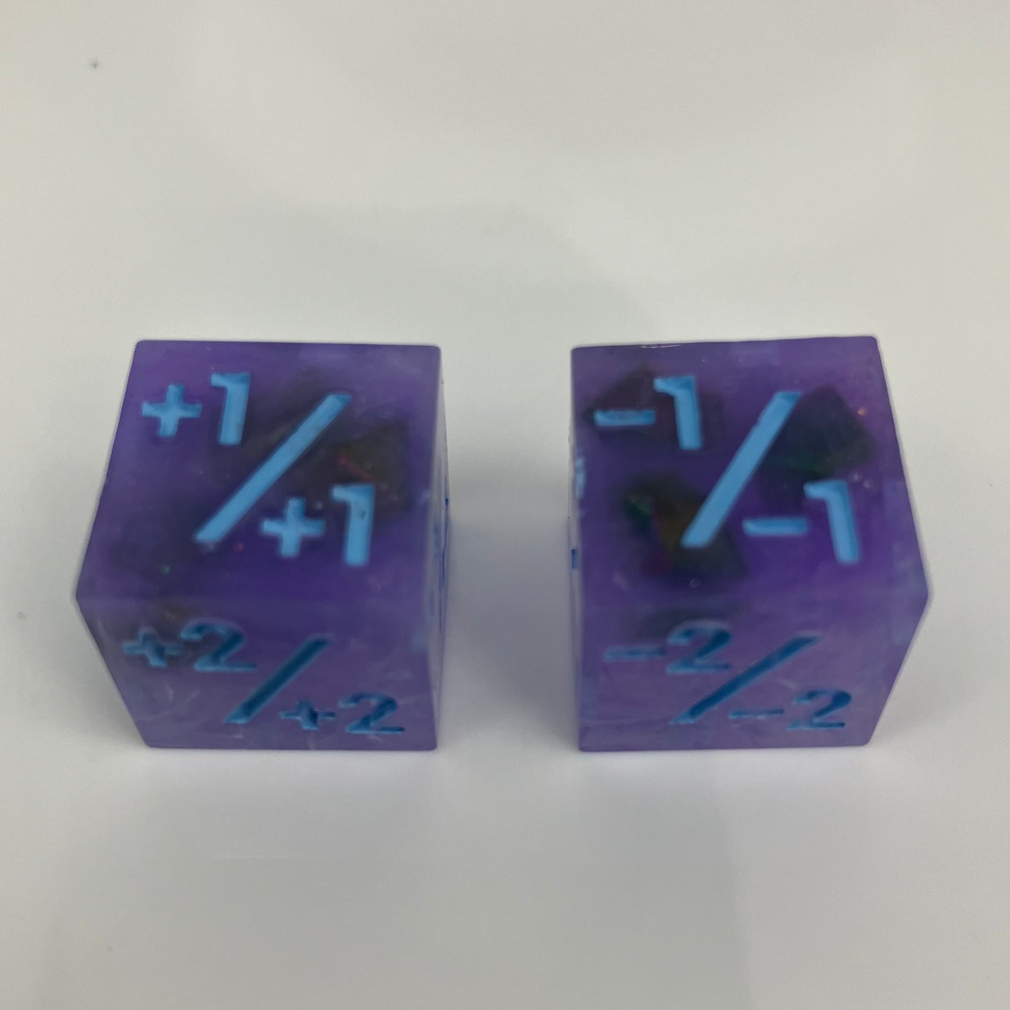 Two purple dice with blue numbers and iridescent rocks