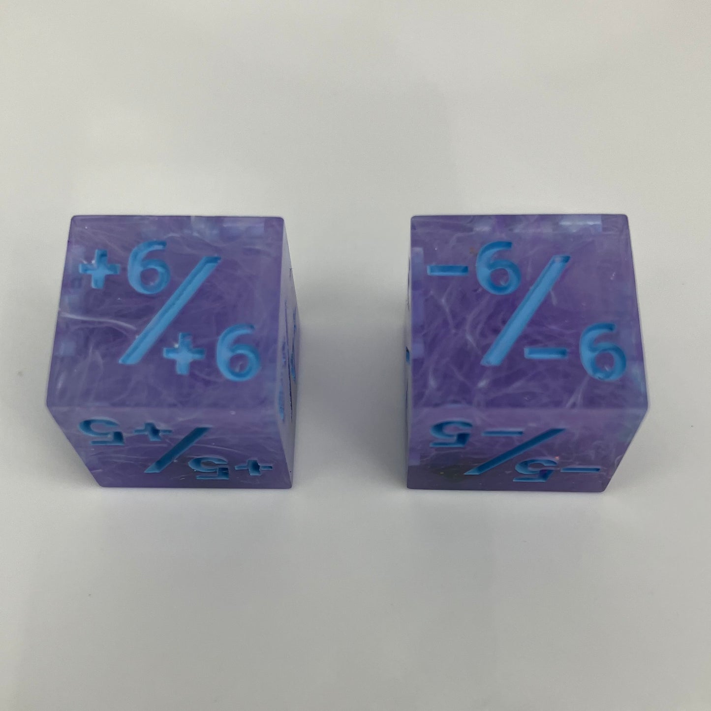 Two purple dice with blue numbers and iridescent rocks