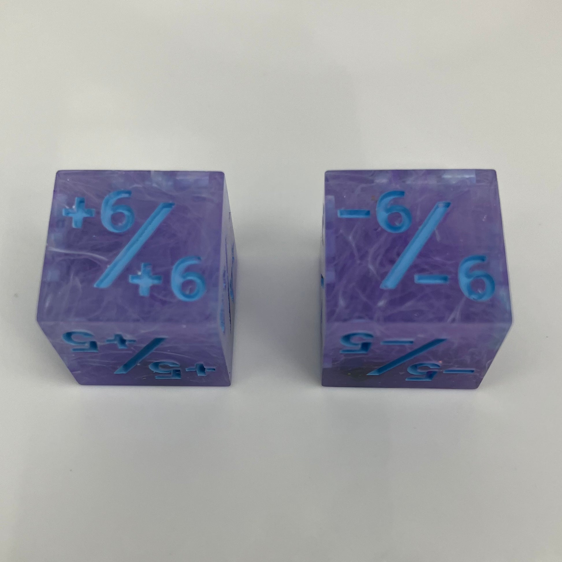 Two purple dice with blue numbers and iridescent rocks