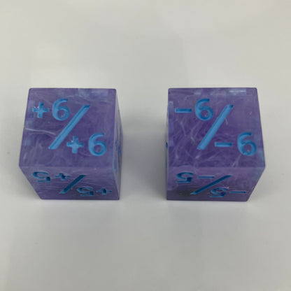 Two purple dice with blue numbers and iridescent rocks