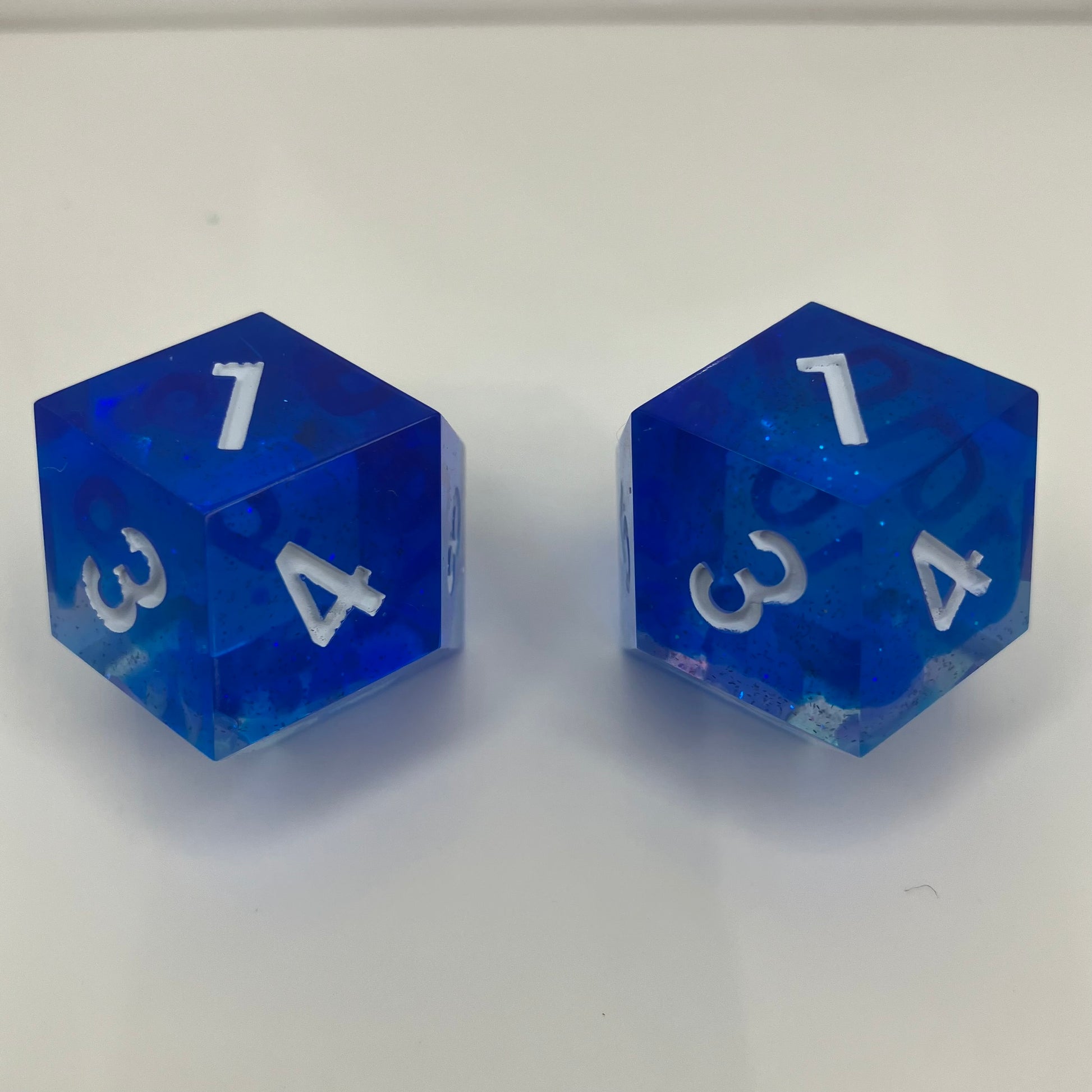Two blue transparent dice with white numbers for daggerheart ttrpg