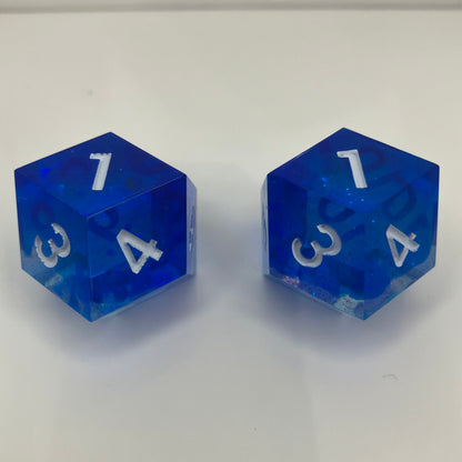 Two blue transparent dice with white numbers for daggerheart ttrpg